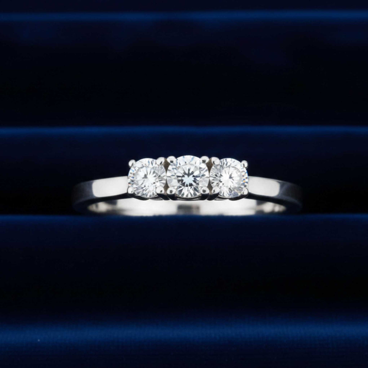 Anello Trilogy in oro bianco 18kt con tre diamanti naturali da 0,90 ct totali su velluto burgundy.