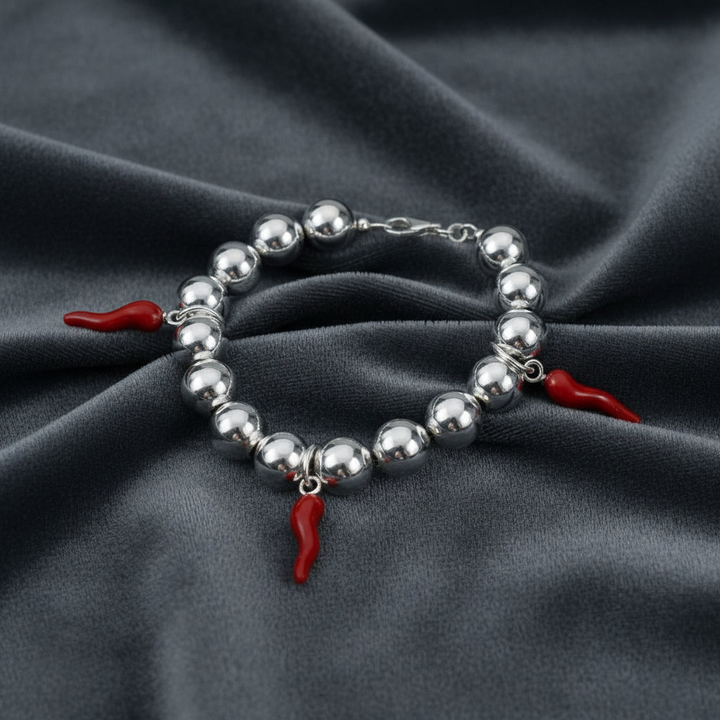Bracciale in argento 925 con sfere da 8mm e cornetti rossi portafortuna su velluto grigio antracite a onde.