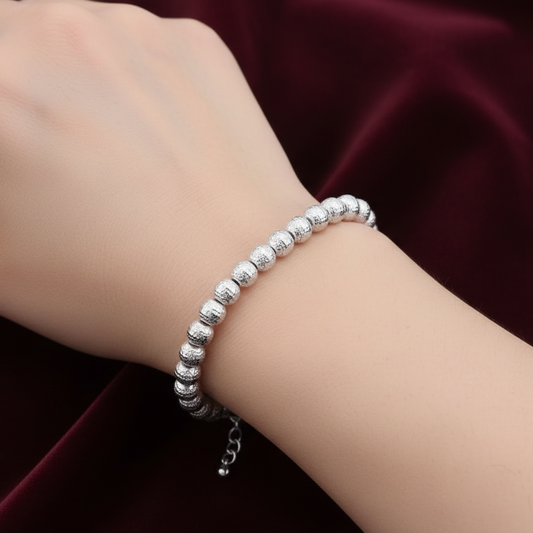 Bracciale Milleluci in oro bianco 18kt con sfere diamantate da 6mm, peso 6.10g, presentato su velluto bordeaux a onde.