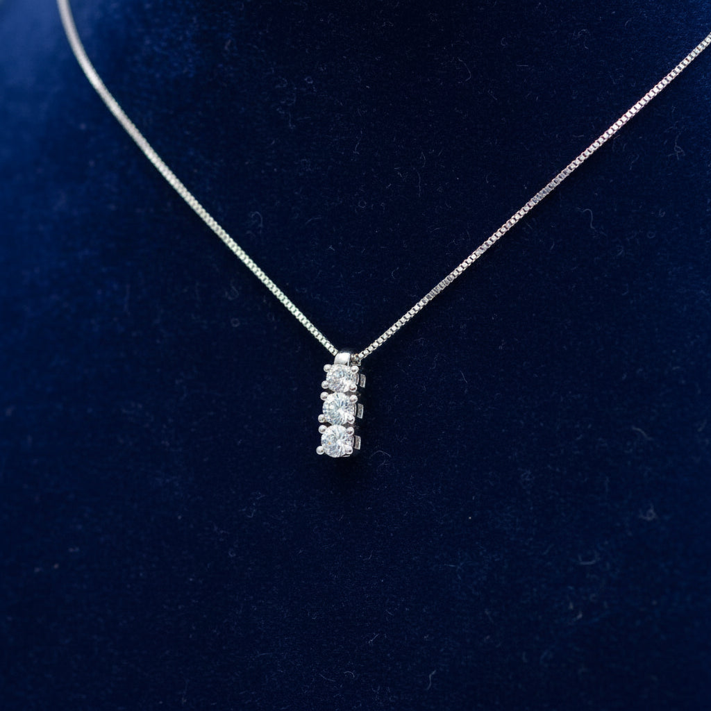 Collana Trilogy Art MiD in oro bianco 18kt con tre diamanti naturali bianchi su velluto blu a onde.