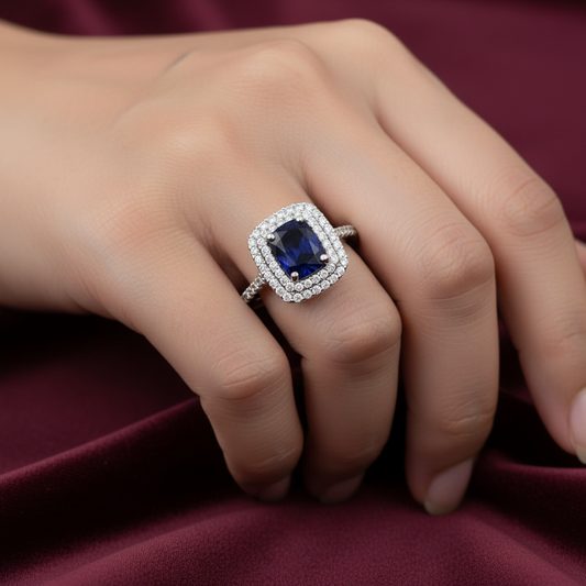 Dettaglio montatura a corona con pietra blu zaffiro in oro bianco 750 su velluto bordeaux.