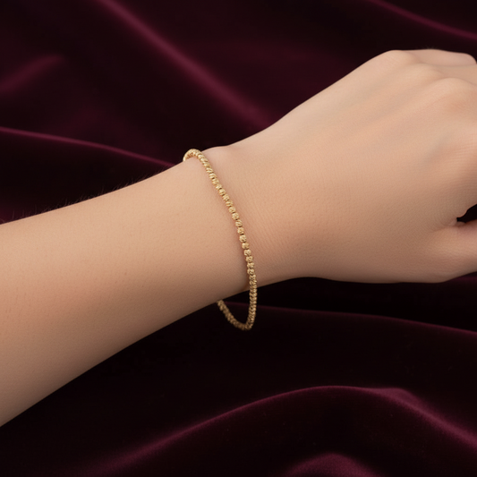 Dettaglio design a sfere 0,15 mm del bracciale in oro giallo 750 peso 2,20g su astuccio effetto onda.