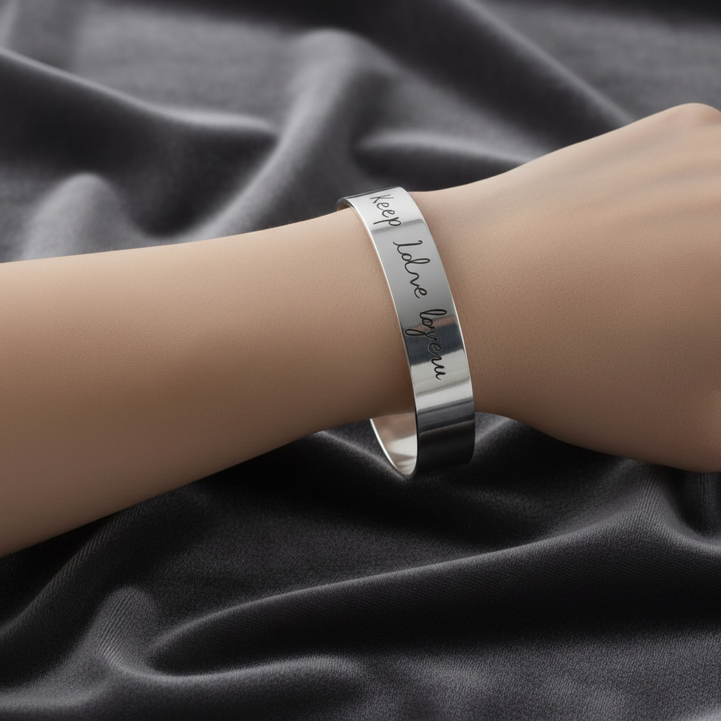 Primo piano dell'incisione nomi personalizzati su bracciale a fascia in argento rodiato ArtMID.