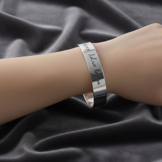 Primo piano dell'incisione nomi personalizzati su bracciale a fascia in argento rodiato ArtMID.