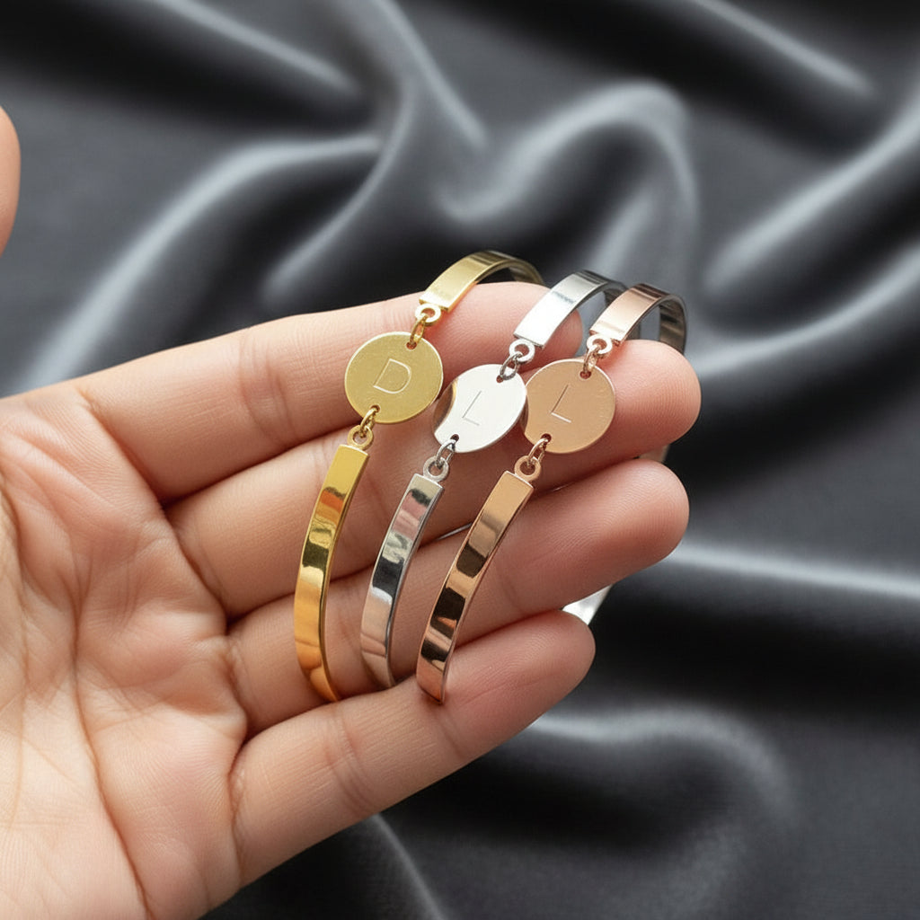 Primo piano della medaglia con lettera incisa in corsivo su bracciale rigido ArtMID