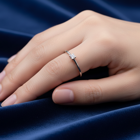 Dettaglio montatura a griffe del solitario in oro 750 su velluto bordeaux a onde.