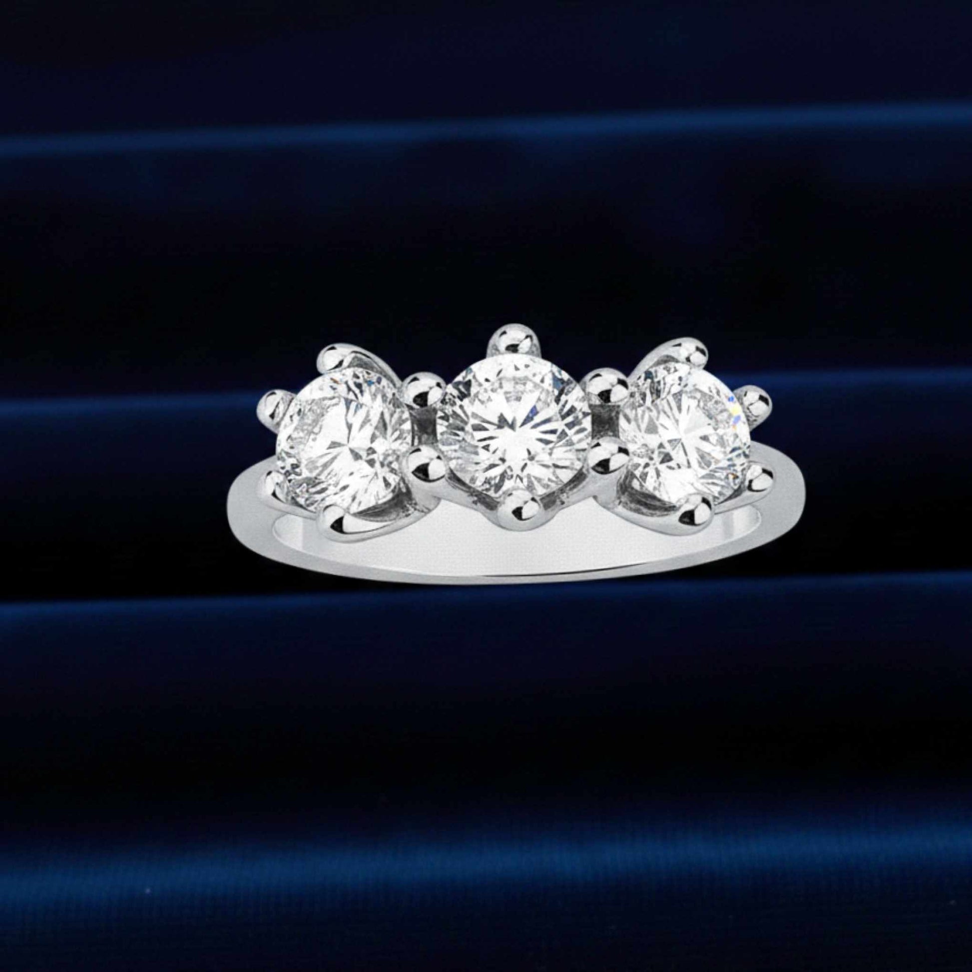 Anello Trilogy d'alta gioielleria con tre grandi diamanti naturali da 3,30 ct totali su velluto burgundy.