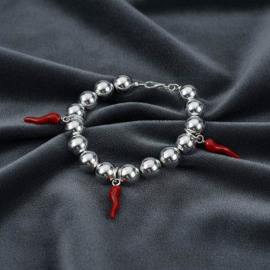 Bracciale in argento 925 con sfere da 8mm e cornetti rossi portafortuna su velluto grigio antracite a onde.