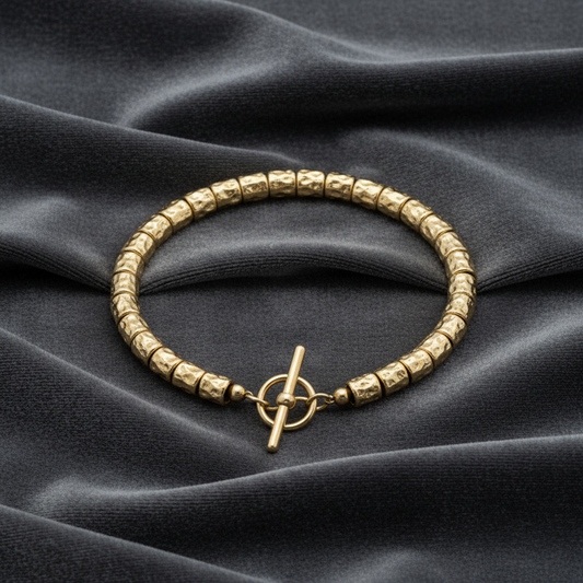 Bracciale a filo singolo in argento 925 placcato oro giallo con pepite e granelli su velluto verde bosco a onde.