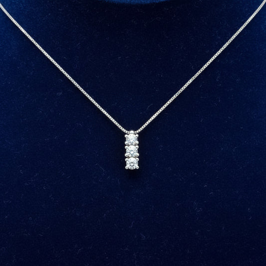 Collana Trilogy Art MiD in oro bianco 18kt con tre diamanti naturali da 0.15 carati su velluto blu a onde.