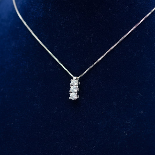 Collana Trilogy Art MiD in oro bianco 18kt con tre diamanti naturali bianchi su velluto blu a onde.