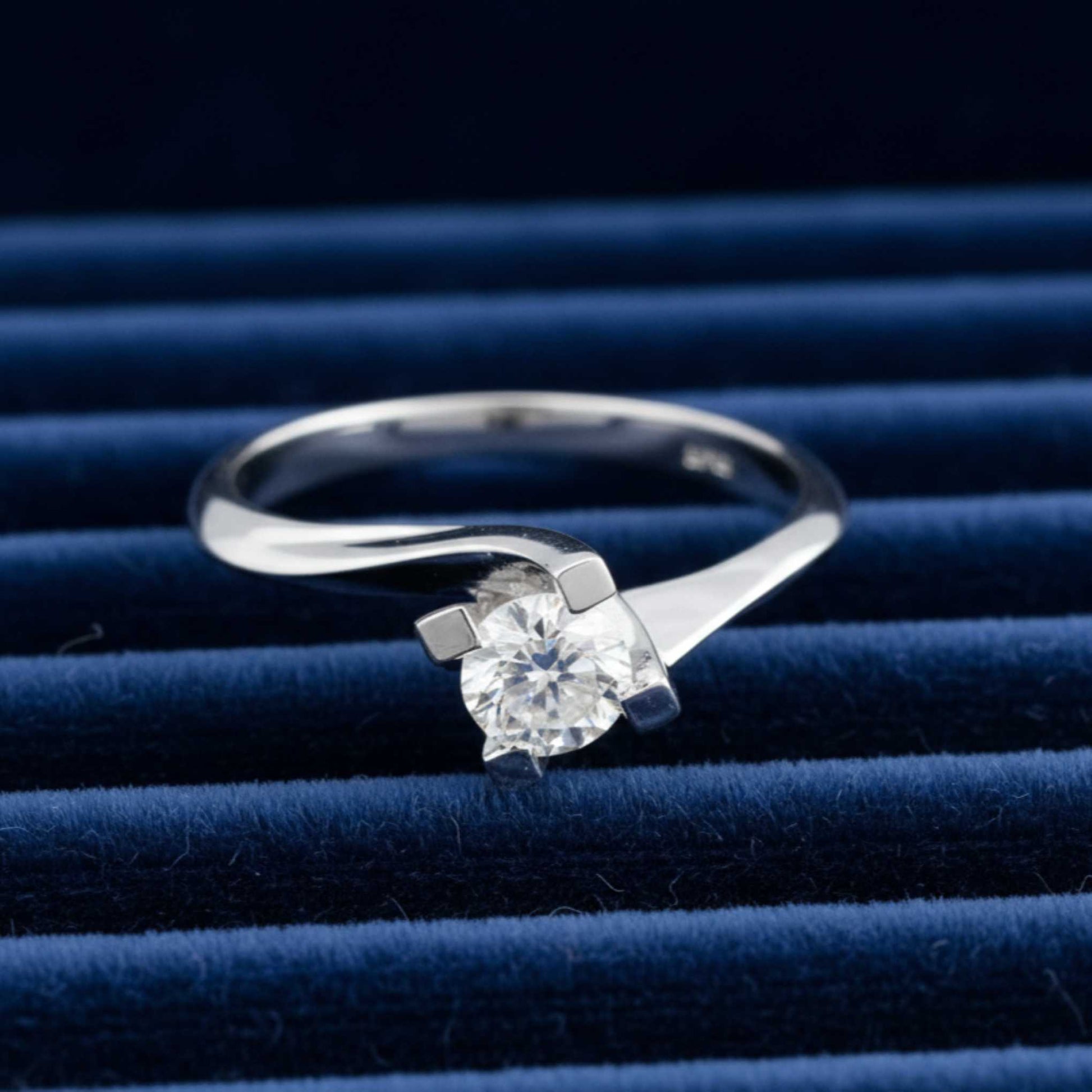 Anello solitario modello Valentino in oro bianco 18kt con diamante da 0.35 ct adagiato su velluto burgundy